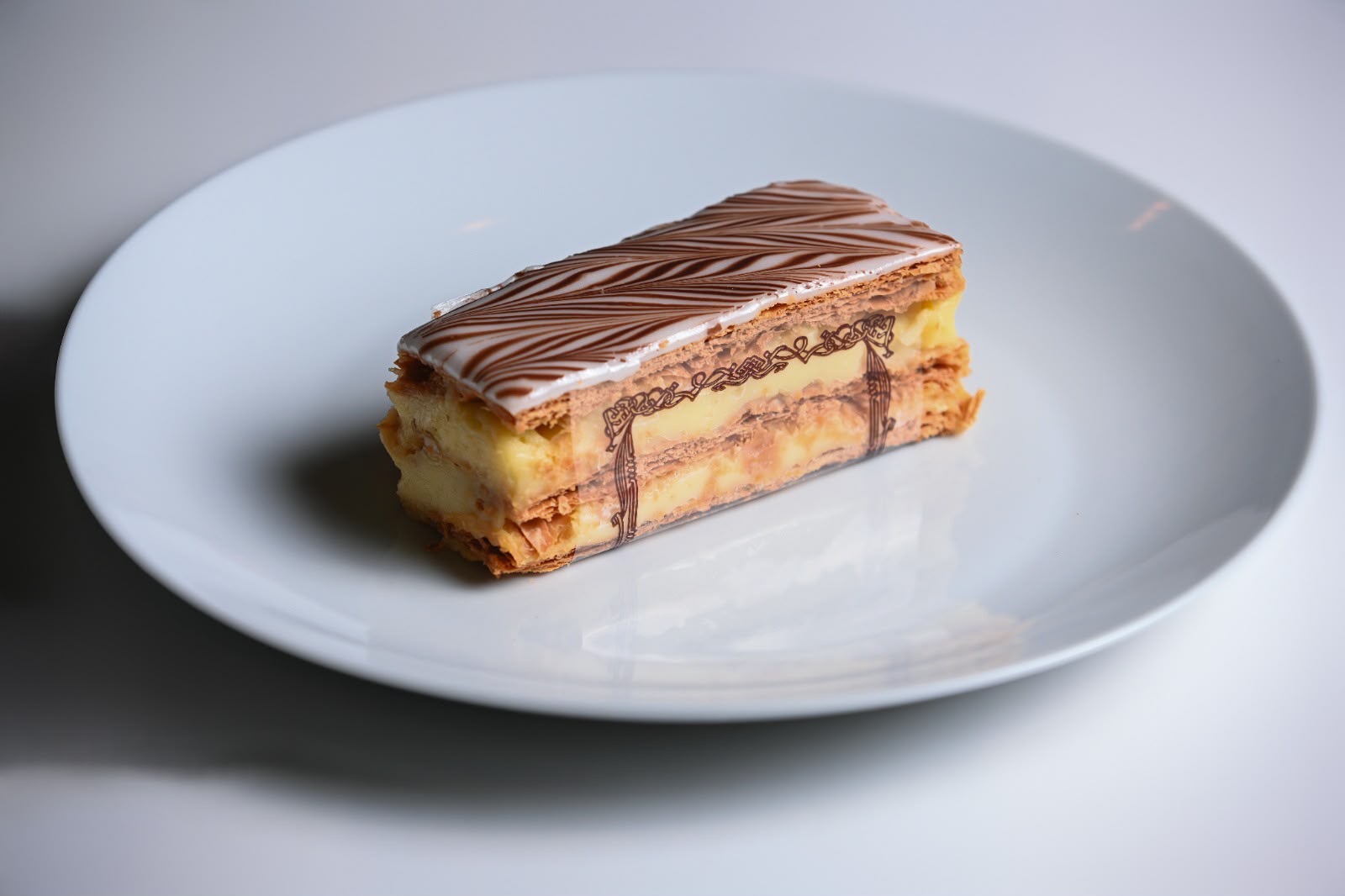 Mille-feuille slice with vanilla cream and feathered chocolate icing