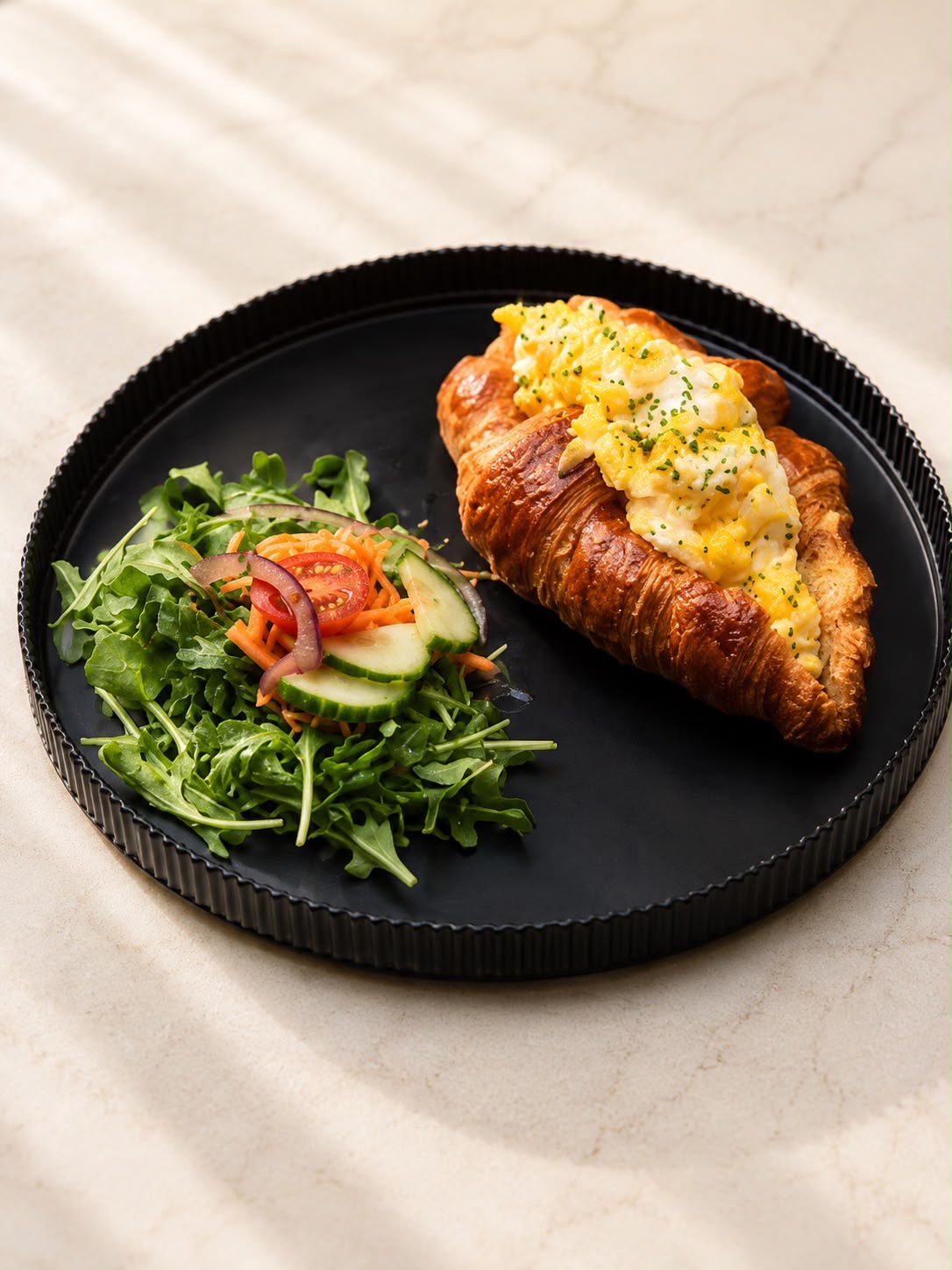 Croissant filled with soft scrambled eggs and chives, side salad