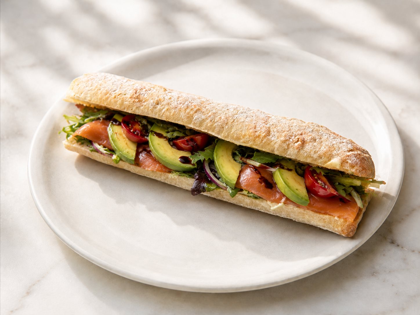Baguette with smoked salmon, avocado, cherry tomato and balsamic glaze